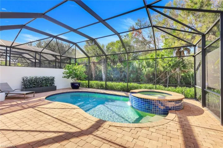 View of swimming pool featuring an in ground hot tub, glass enclosure, and a patio area