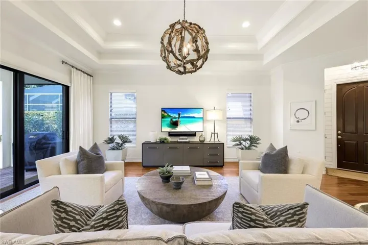 Living room featuring hardwood / wood-style flooring, ornamental molding, and a tray ceiling