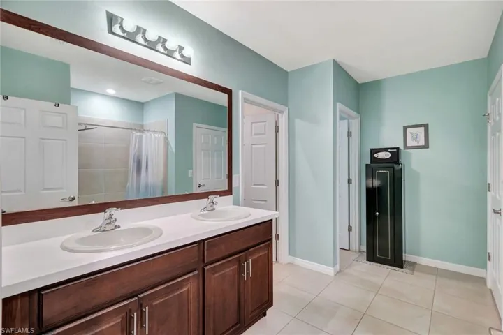 Bathroom featuring double vanity, a shower with shower curtain, a sink, and tile patterned flooring