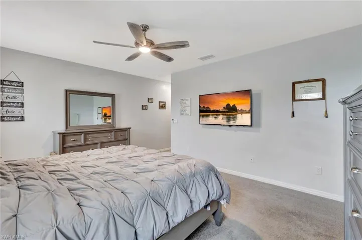 Bedroom featuring baseboards, visible vents, ceiling fan, and carpet