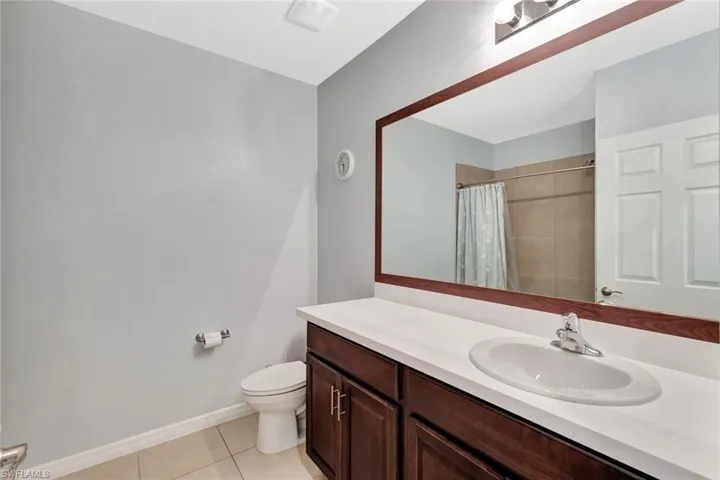 Bathroom with baseboards, toilet, vanity, a shower with curtain, and tile patterned flooring