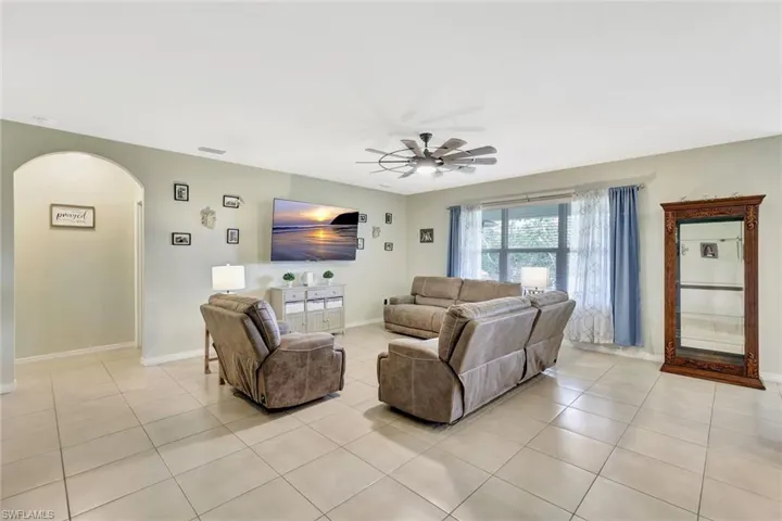 Living room featuring visible vents, baseboards, ceiling fan, arched walkways, and light tile patterned floors