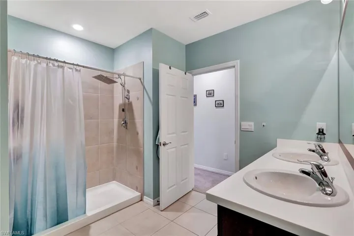 Full bathroom with tile patterned floors, visible vents, a tile shower, and a sink