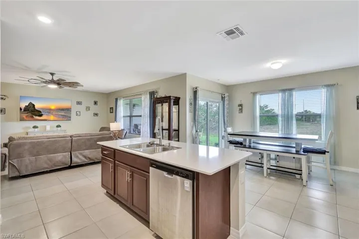 Kitchen featuring visible vents, a sink, open floor plan, stainless steel dishwasher, and light tile patterned floors