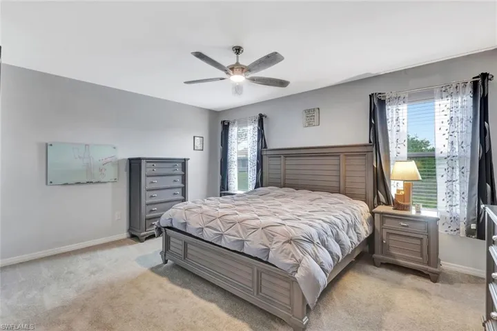 Bedroom with a ceiling fan, light carpet, and baseboards