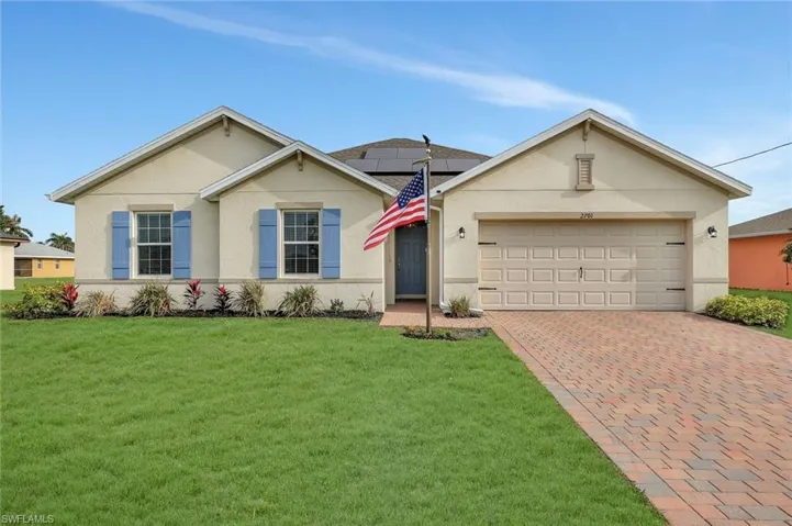 Ranch-style home featuring stucco siding, a garage, a front yard, and decorative driveway