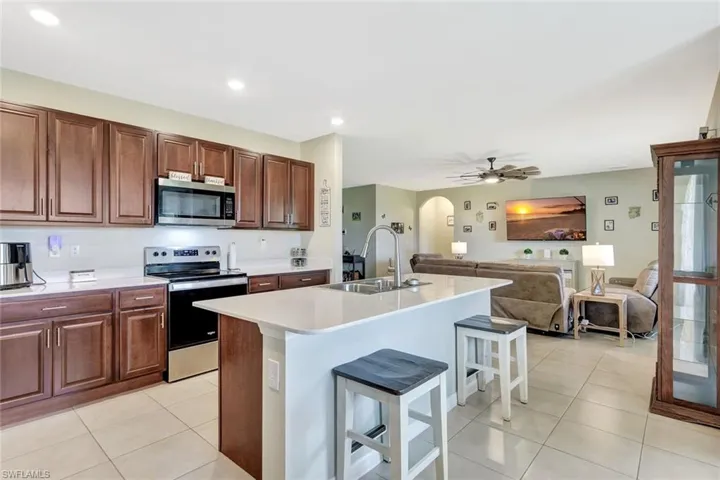 Kitchen featuring a breakfast bar area, light tile patterned floors, stainless steel appliances, a sink, and arched walkways