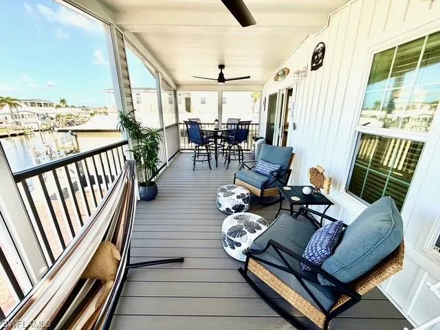 Deck featuring outdoor dining space, a sunroom, a ceiling fan, and a water view