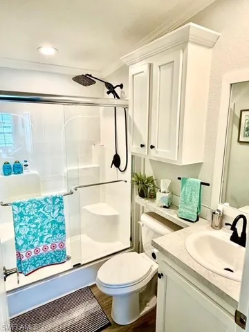 Bathroom with vanity, a stall shower, dark wood-type flooring, and ornamental molding