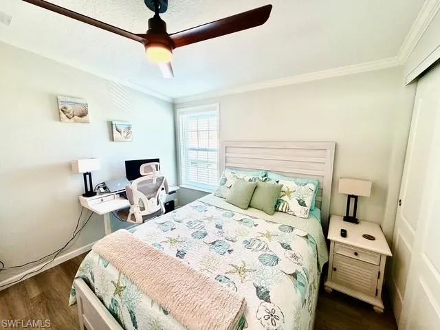 Bedroom featuring ceiling fan, a closet, dark wood-type flooring, and ornamental molding