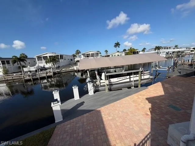 Dock area featuring a water view, boat lift, and a residential view