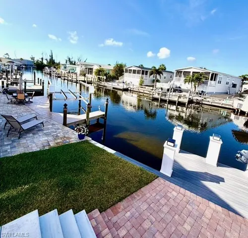 Dock with a yard, a water view, boat lift, and a residential view