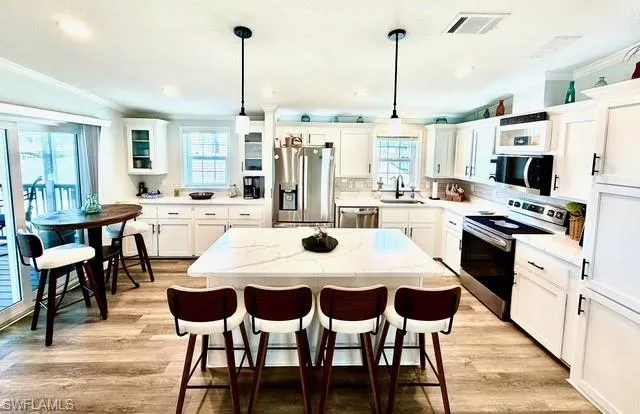 Kitchen with stainless steel appliances, a breakfast bar area, a center island, crown molding, and decorative backsplash
