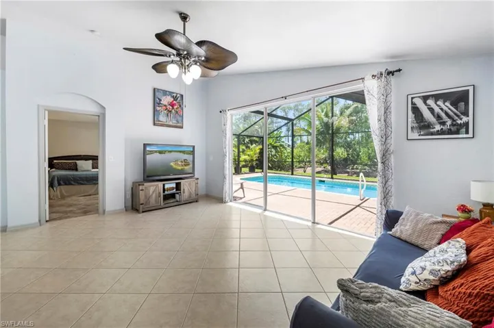 Open-concept living space featuring light-toned tile flooring, neutral wall paint, and a ceiling fan with integrated lighting