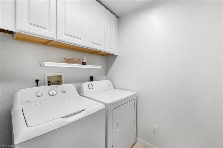 Laundry room featuring white shaker cabinetry, a floating shelf, and neutral wall tones