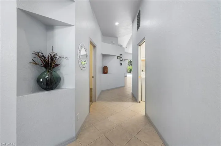 Hallway featuring recessed wall niches, tile flooring, and light-colored walls