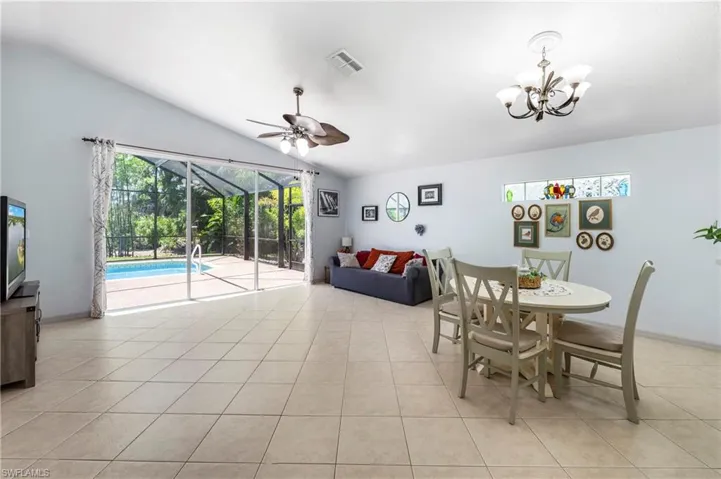 Vaulted ceiling living area featuring large sliding glass doors opening to a screened pool enclosure
