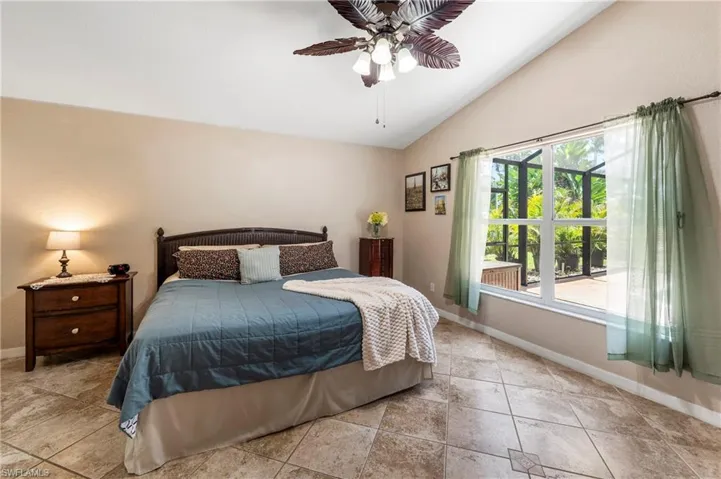 Bedroom featuring vaulted ceilings, large picture window, a decorative ceiling fan, and tile flooring with a patterned inlay