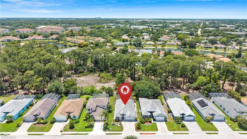 Single-story residence featuring a paved driveway, mature landscaping, and a screened lanai