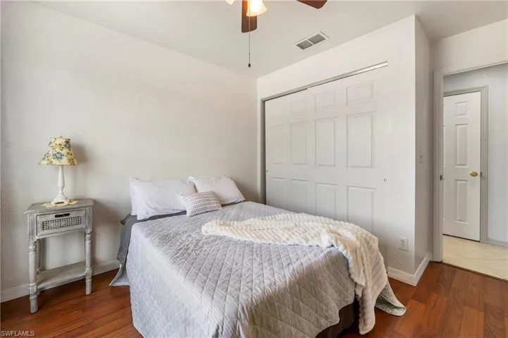 Bedroom featuring wood-finish flooring, a ceiling fan with integrated lighting, and a sliding panel closet with white paneled doors