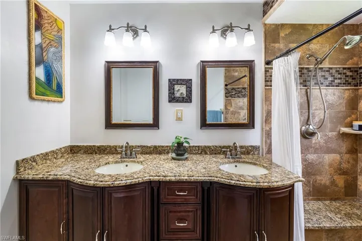 Dual vanity with granite countertops, undermount sinks, and dark wood-finish cabinetry