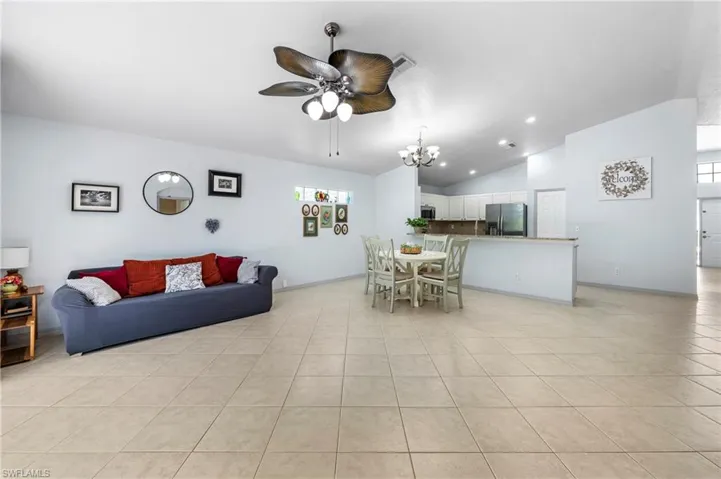 Open-concept living space featuring light-toned tile flooring, neutral wall paint, and a ceiling fan with integrated lighting
