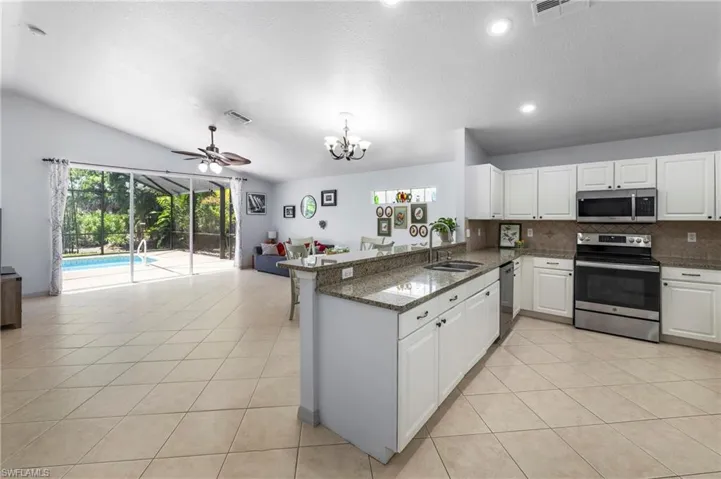Spacious open-concept interior featuring light tile flooring, vaulted ceilings, and recessed lighting