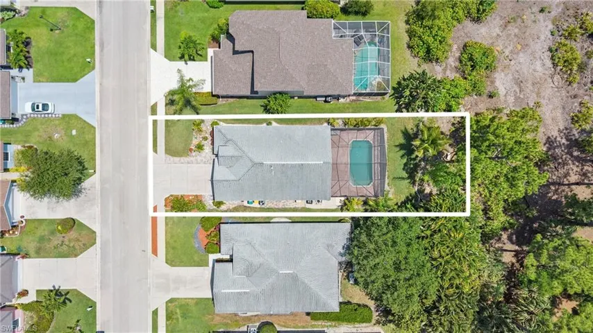 Aerial view showcasing a residential property with a screened swimming pool and surrounding paved patio
