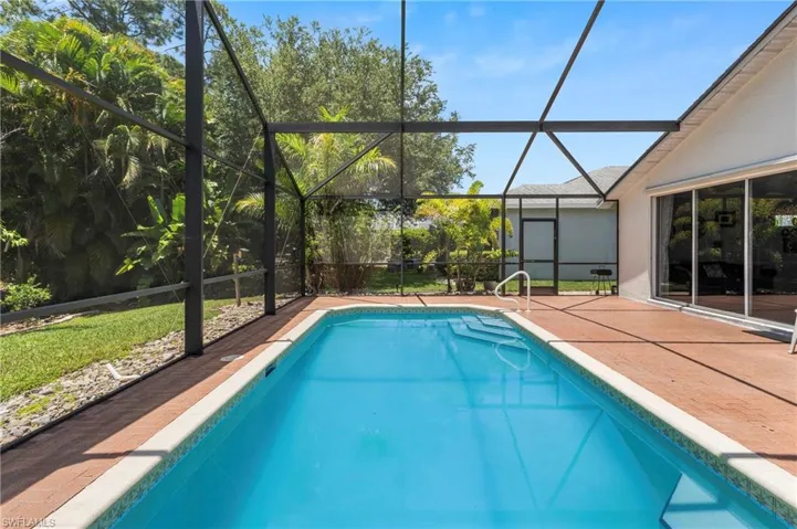 Screened enclosure with an in-ground pool featuring integrated steps and a handrail
