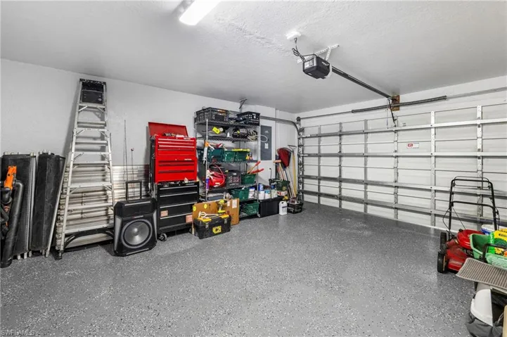 Spacious garage featuring a durable epoxy floor, overhead lighting, and an automatic garage door opener