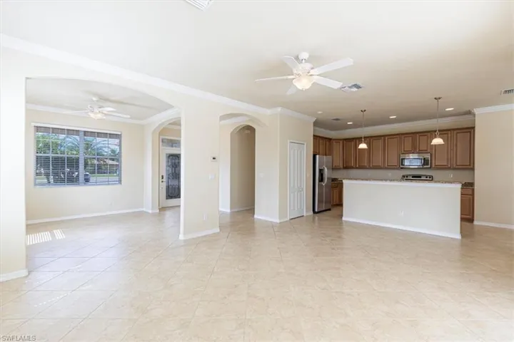Unfurnished living room with ceiling fan, crown molding, arched walkways, and light tile patterned flooring