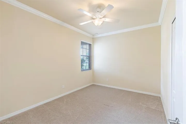 Spare room featuring ornamental molding, light carpet, and a ceiling fan