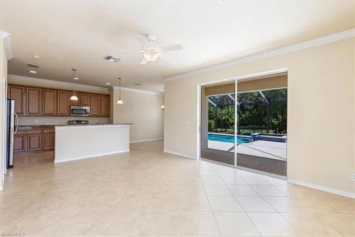Unfurnished living room featuring crown molding, ceiling fan, a sunroom, and light tile patterned flooring