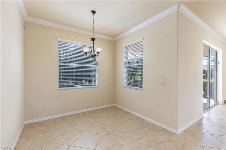 Unfurnished dining area with crown molding, a chandelier, plenty of natural light, and light tile patterned flooring
