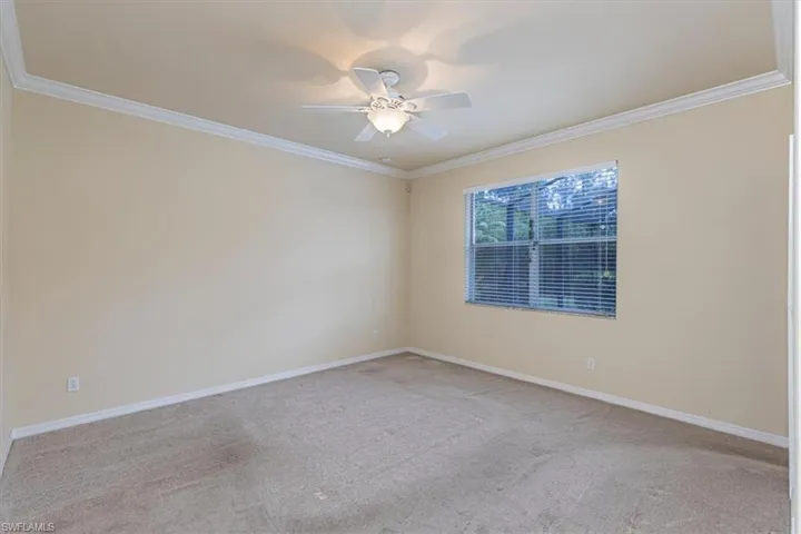 Empty room featuring crown molding, light carpet, and a ceiling fan