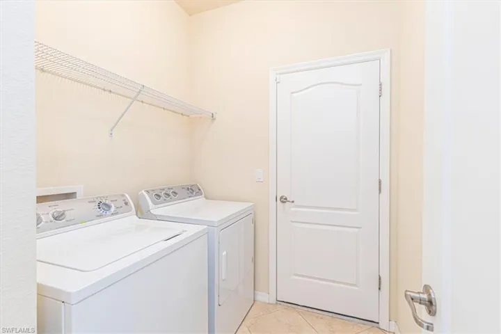 Laundry area with light tile patterned floors and washing machine and clothes dryer