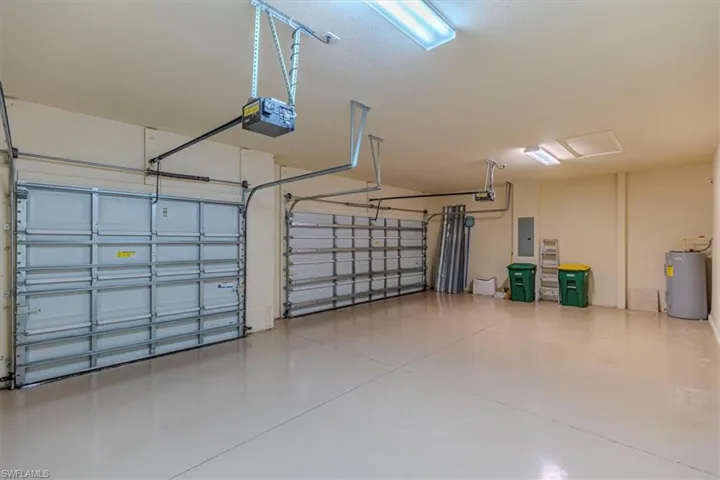 Garage featuring electric water heater, a garage door opener, and electric panel