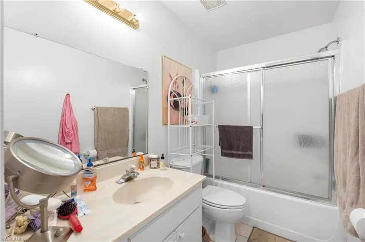 Full bathroom featuring vanity, toilet, shower / bath combination with glass door, and tile patterned floors