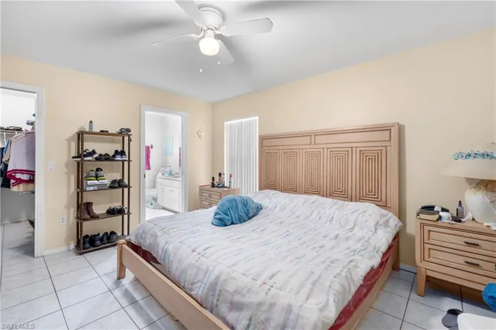 Bedroom featuring light tile patterned flooring, a walk in closet, a closet, baseboards, and ceiling fan