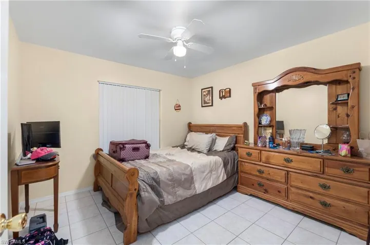 Bedroom featuring light tile patterned flooring, a ceiling fan, and baseboards