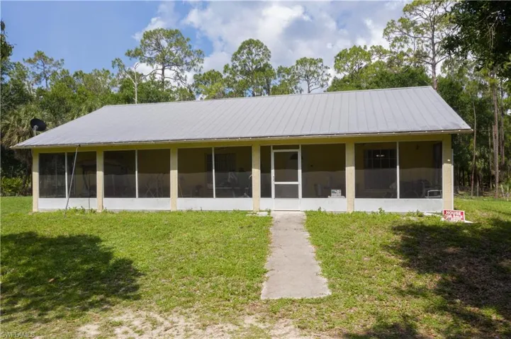 Front of property featuring a sunroom, a lawn, and metal roof