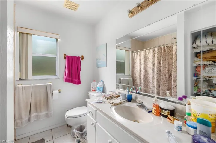 Bathroom featuring tile patterned floors, vanity, toilet, and curtained shower
