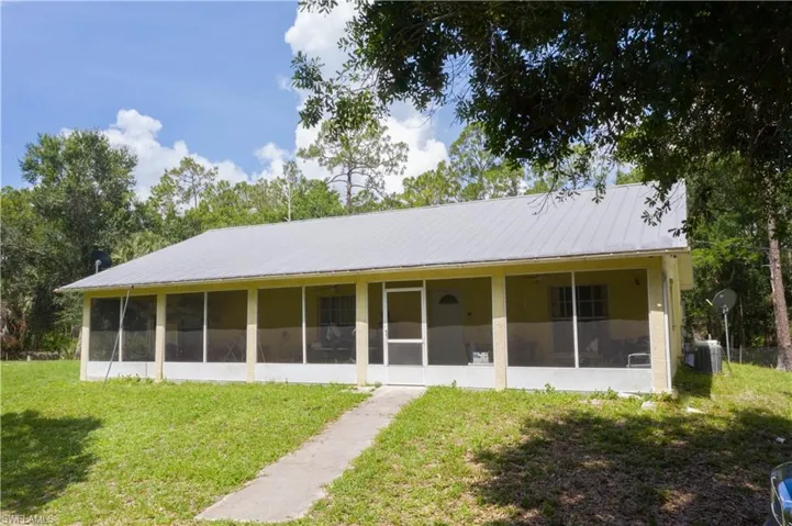 Front of house with a sunroom, a yard, and metal roof