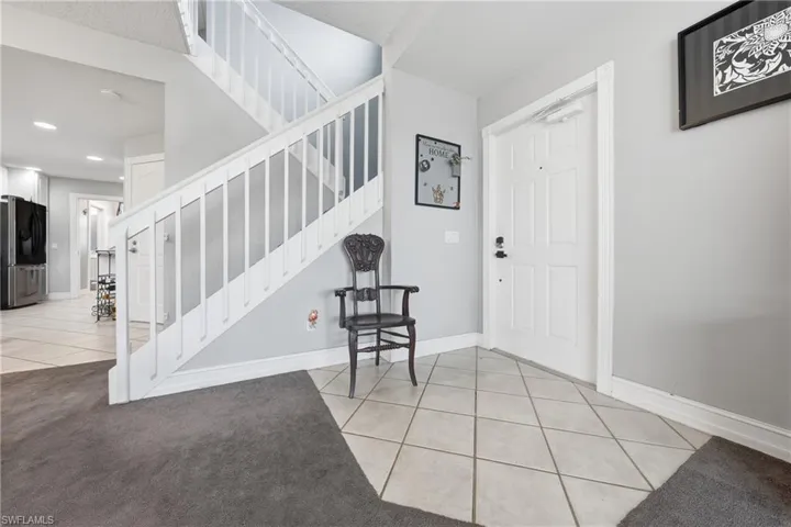 Entryway featuring a white panel door, light gray wall paint, and square tile flooring