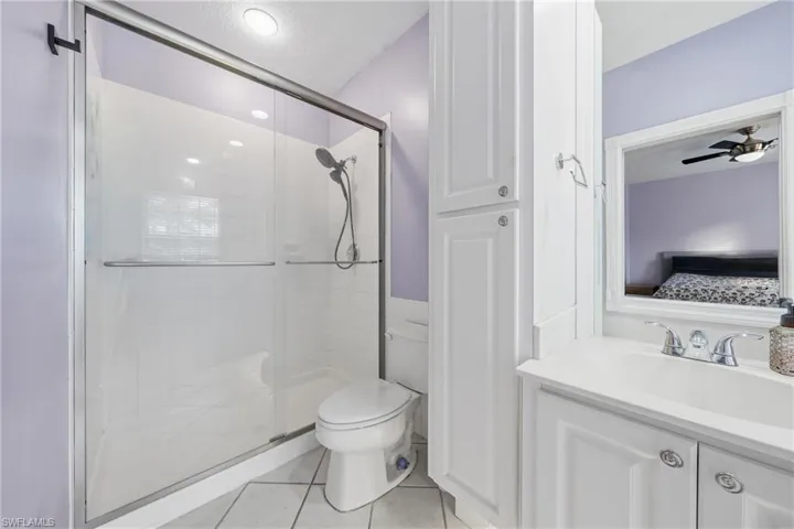 Bathroom featuring a glass-enclosed shower, white vanity with integrated sink, chrome fixtures, and built-in storage cabinetry
