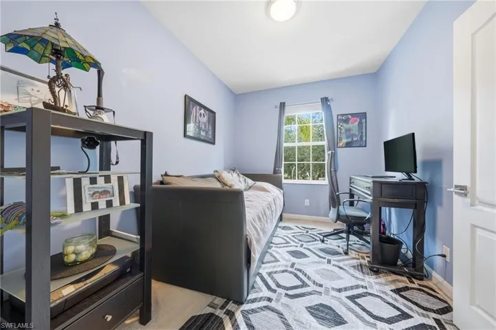 Bright interior room featuring a window with exterior tree views, light blue painted walls, a flush-mount ceiling light, and white trim