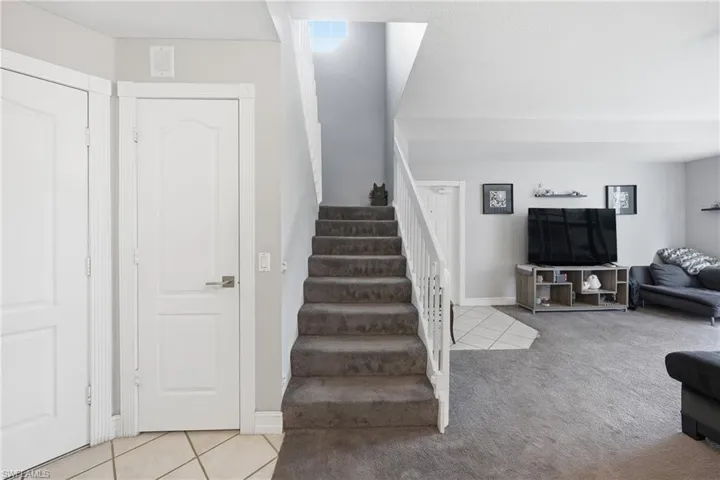 Carpeted staircase with white balusters and handrail