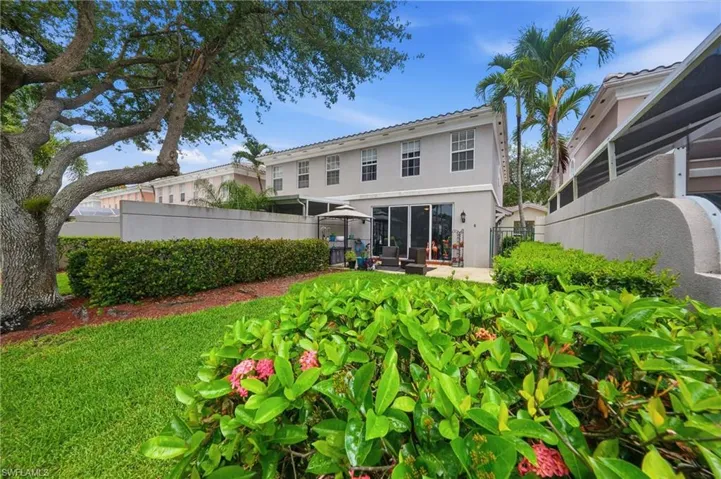 Spacious backyard featuring a manicured lawn, established landscaping, and mature trees