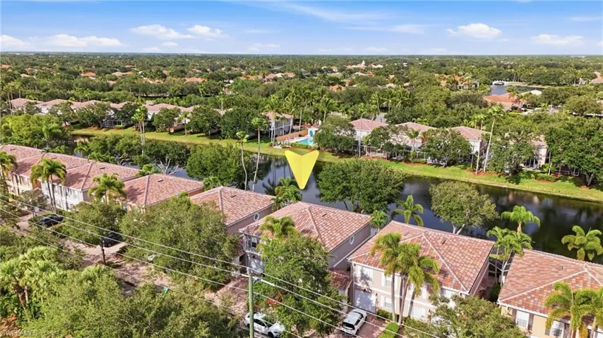 Aerial perspective of a residential community featuring a canal, tile roofs, mature trees, and surrounding properties