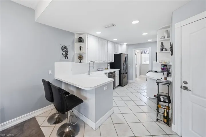 Kitchen featuring white cabinetry, light-colored countertops, stainless steel appliances, and diagonal tile flooring